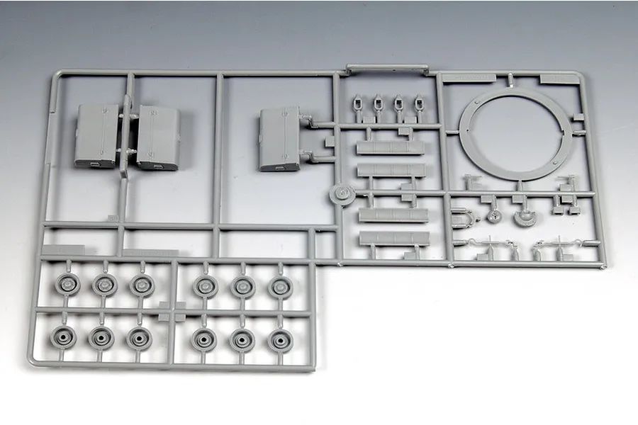 A grey plastic sprue from a 1/35 scale model kit containing various tank parts including road wheels and turret components.
