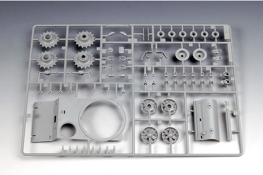 A grey plastic sprue containing various tank model parts, including wheels, sprockets, and hull components for a 1/35 scale model kit.