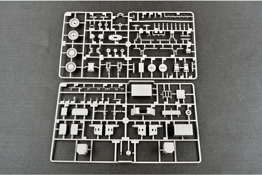 Two grey plastic model kit sprues containing various vehicle parts laid out on a dark grey surface.
