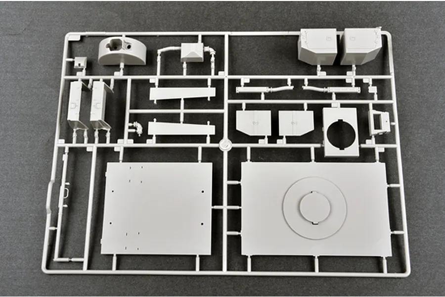 A grey plastic sprue containing various unpainted model kit parts for a military vehicle on a dark background.