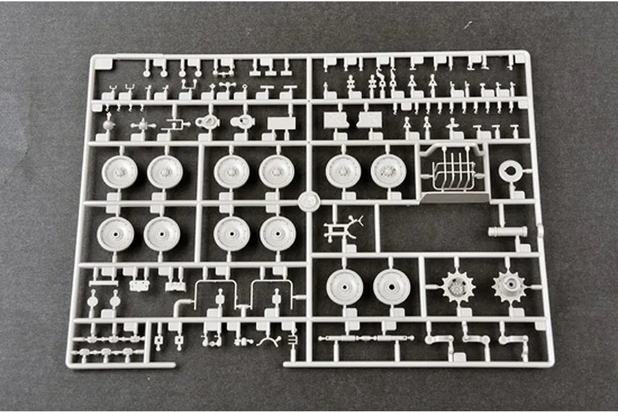 A grey plastic model kit sprue containing various tank wheels, sprockets, and small mechanical parts for a 1/35 scale military vehicle model.