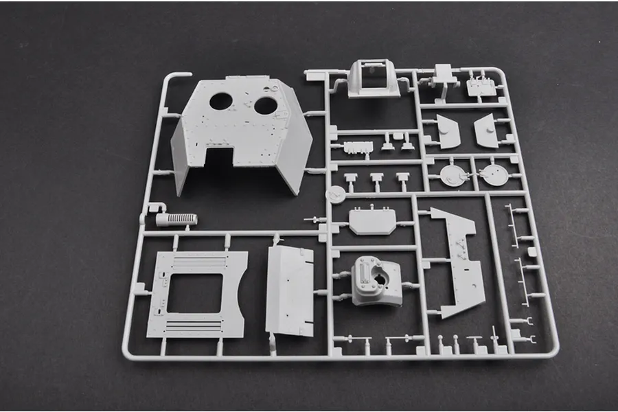 A grey plastic sprue containing various model tank parts, including a large turret section, for a 1/35 scale military model kit.