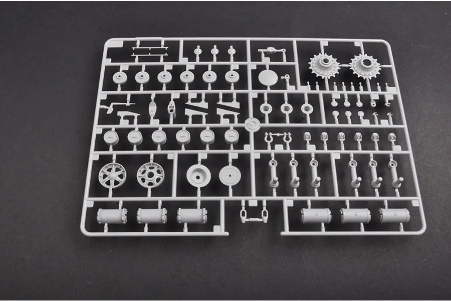 A grey plastic model kit sprue containing various tank suspension and wheel components on a dark background.