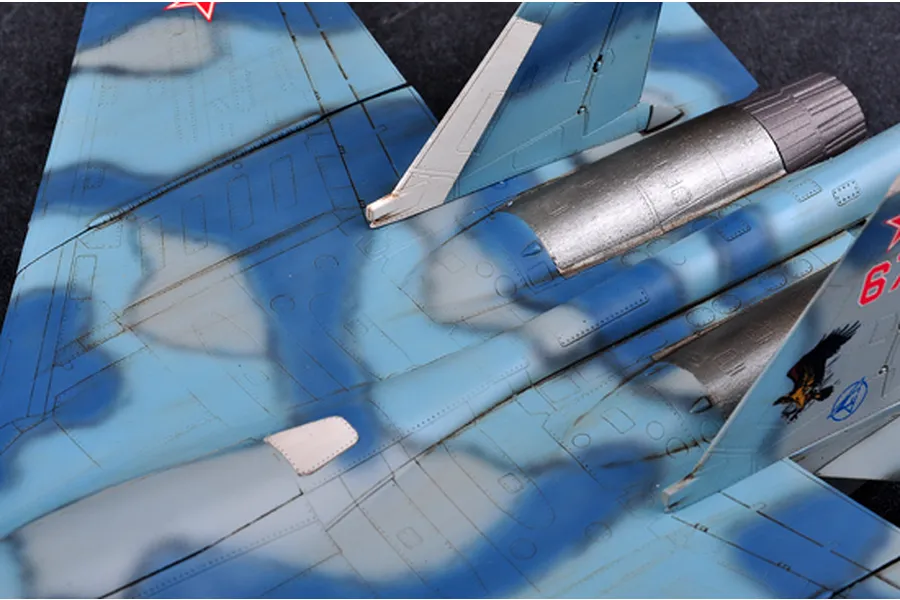Close-up of a scale model Su-33 Flanker D fighter jet showing the blue camouflage paint scheme, metallic engine nozzles, and vertical stabilizer markings.