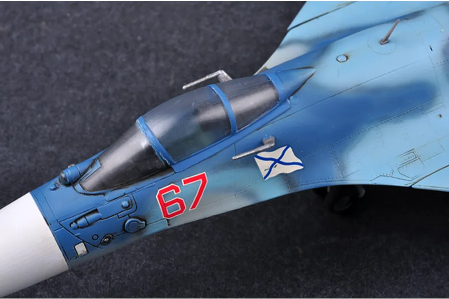 Close-up of a 1/72 scale plastic model Russian Su-33 Flanker fighter jet showing the cockpit, blue camouflage paint, and the number 67 decal.