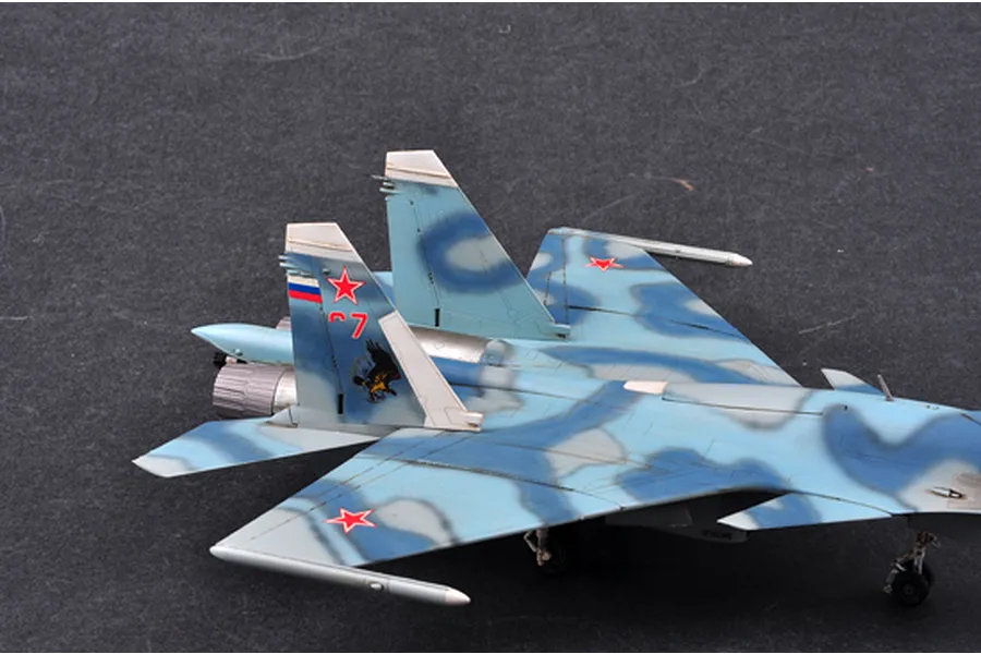 A high-angle view of a 1/72 scale plastic model of a Russian Su-33 Flanker D fighter jet, showing the blue camouflage pattern and tail markings.