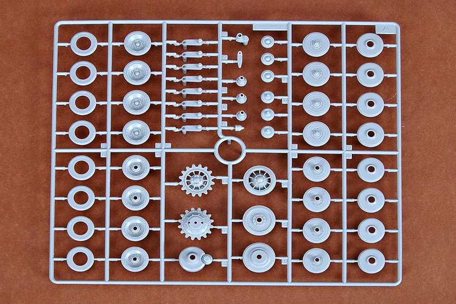 A grey plastic sprue containing various tank road wheels, sprockets, and suspension components for a 1/35 scale model kit.