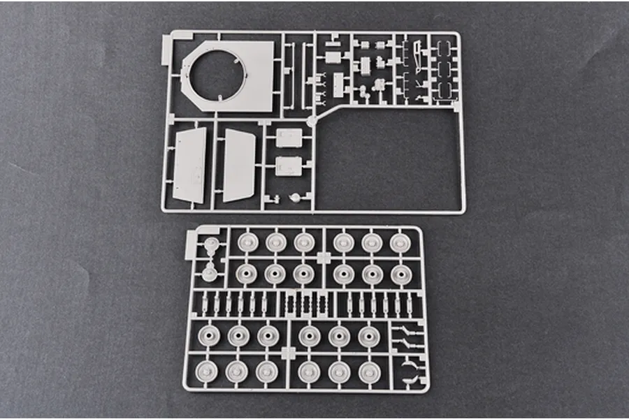 Two grey plastic model kit sprues from a Trumpeter 1/35 scale military vehicle kit, featuring tank hull parts and road wheels on a dark grey background.