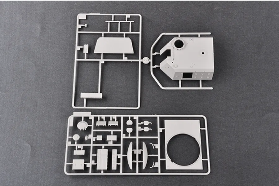 Two light grey plastic model kit sprues containing tank turret and hull components on a dark grey background.