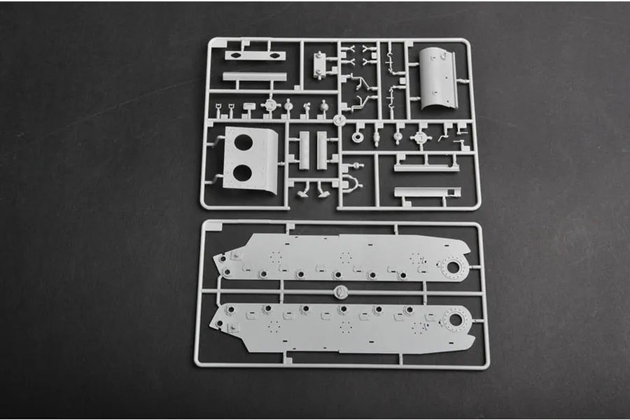 Two grey plastic model kit sprues containing tank hull and detail parts on a dark grey background.