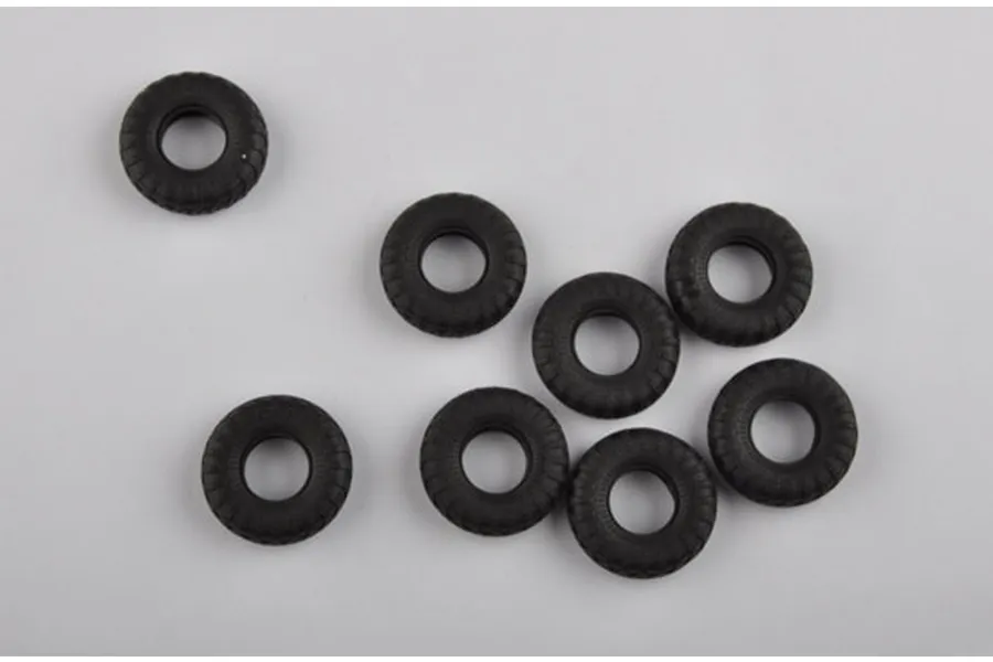 Eight black rubber model vehicle tires arranged on a plain white background.