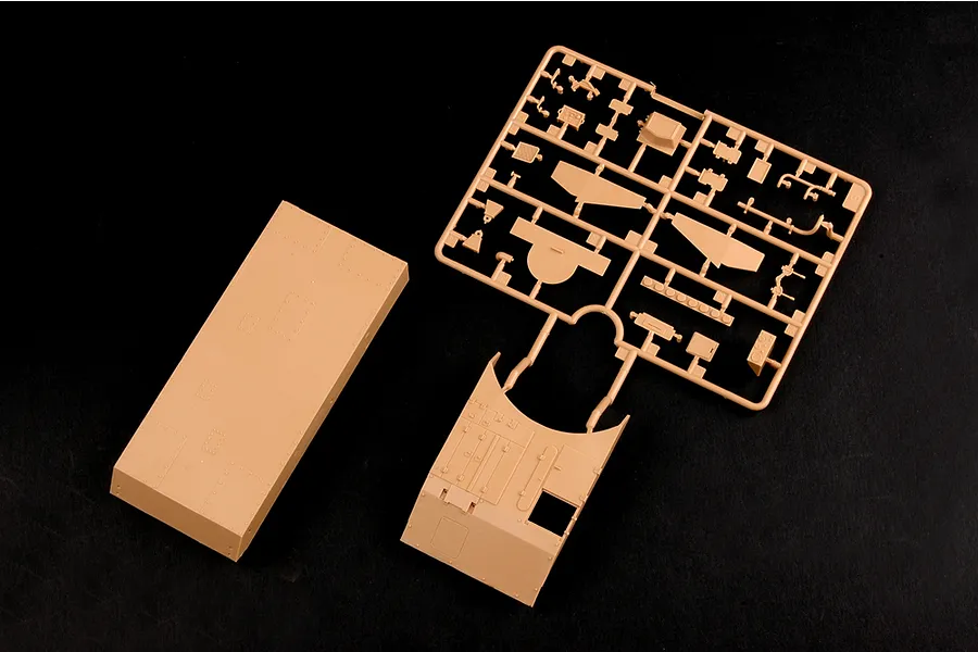 Tan plastic model kit parts including a large hull piece and a sprue frame on a black background.