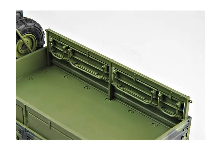 A close-up view of the cargo bed of a 1/35 scale olive drab military truck model kit, showing the interior side panels and a spare tire.