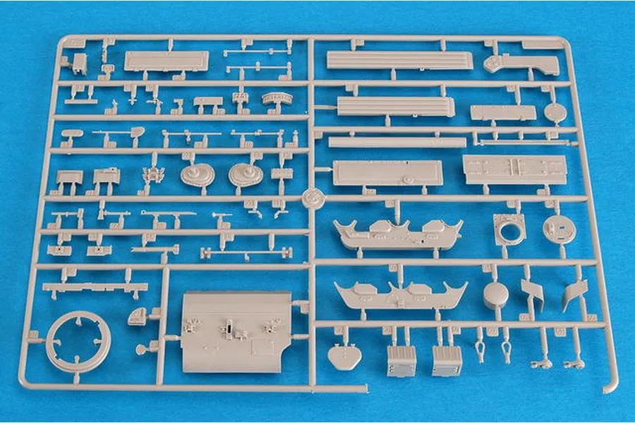 A light grey plastic model kit sprue containing various small parts for a 1/35 scale military vehicle model, set against a bright blue background.