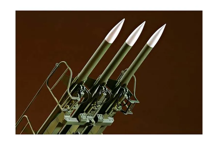 A close-up view of three olive green surface-to-air missiles mounted on a launcher, part of a 1/35 scale plastic model kit.