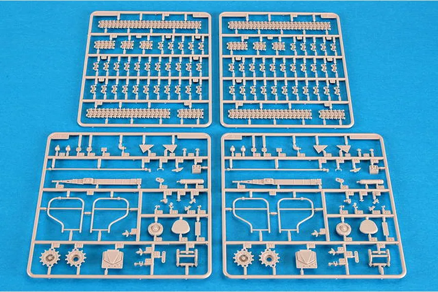 Four plastic model kit sprues laid out on a blue background, featuring tank track links and various vehicle parts for a 1/35 scale model.