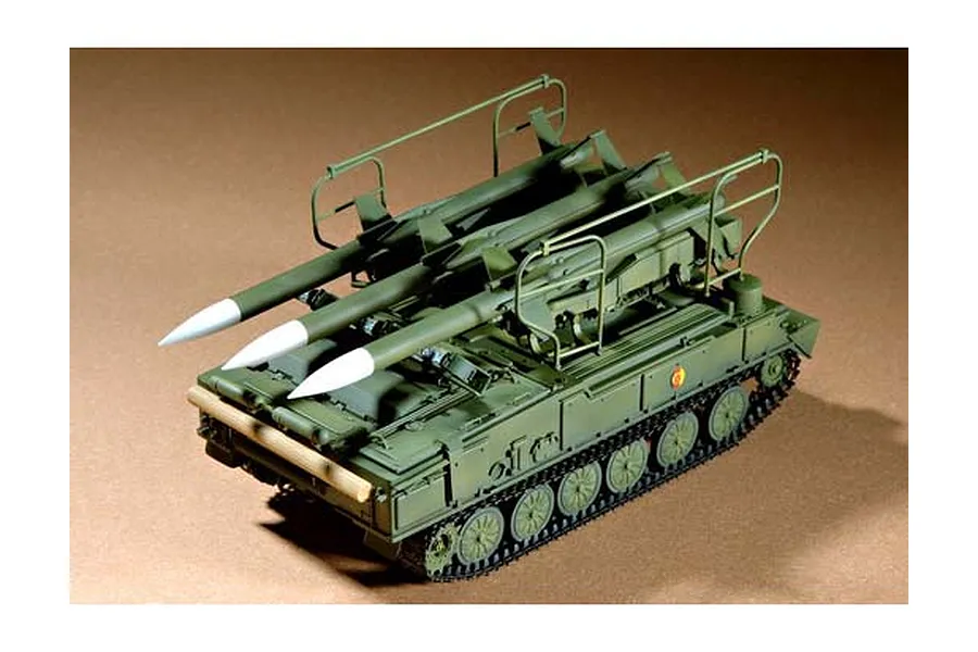 A 1/35 scale plastic model of a Russian SAM-6 anti-aircraft missile vehicle, painted in olive green with three white-tipped missiles mounted on top.