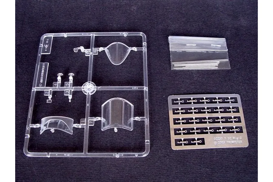 Clear plastic sprue containing aircraft canopy parts, a small metal photo-etched fret, and a bag of metal rods for a 1/32 scale MiG-3 model kit.