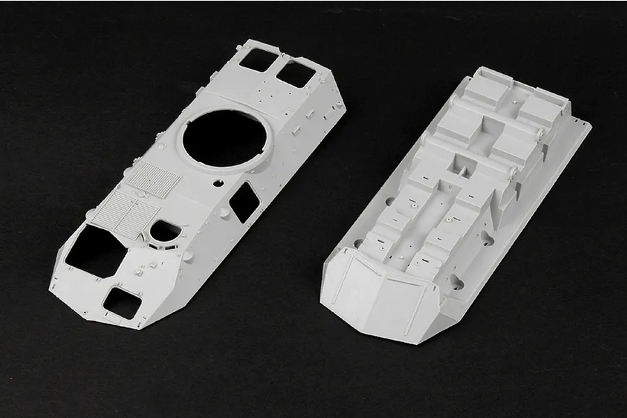 Two unpainted grey plastic model kit parts for an LAV-25 armoured vehicle, showing the upper hull and lower chassis components.