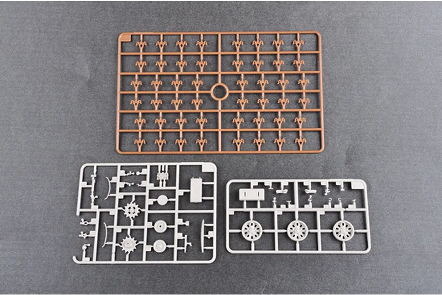 Three plastic model kit sprues from a Trumpeter tank kit, including one brown sprue and two grey sprues on a grey background.