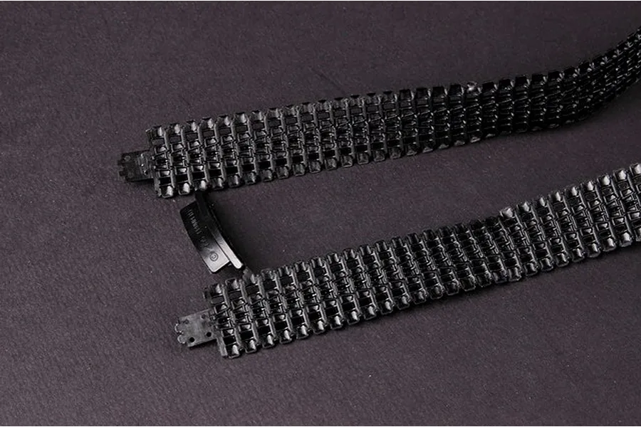 Close-up of two black plastic tank track segments for a 1/35 scale model kit on a dark grey background.
