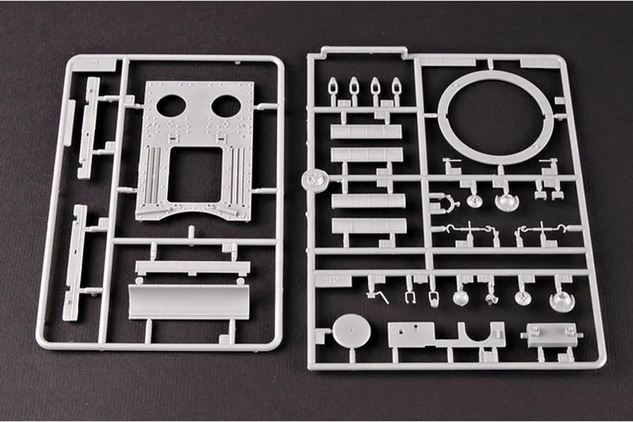 Two grey plastic model kit sprues containing various tank parts on a dark background.