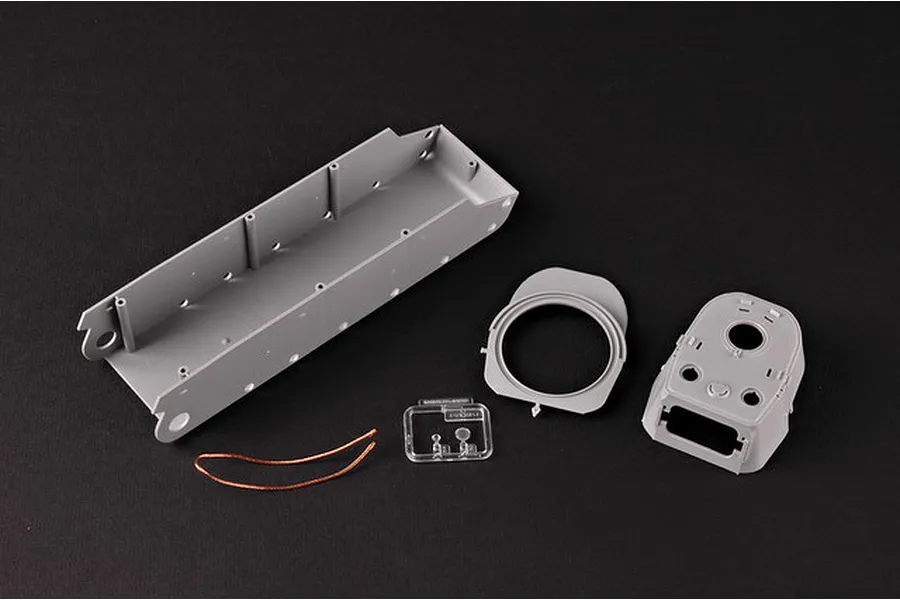 Unassembled plastic model tank parts including the hull, turret, clear parts, and a copper wire on a black background.