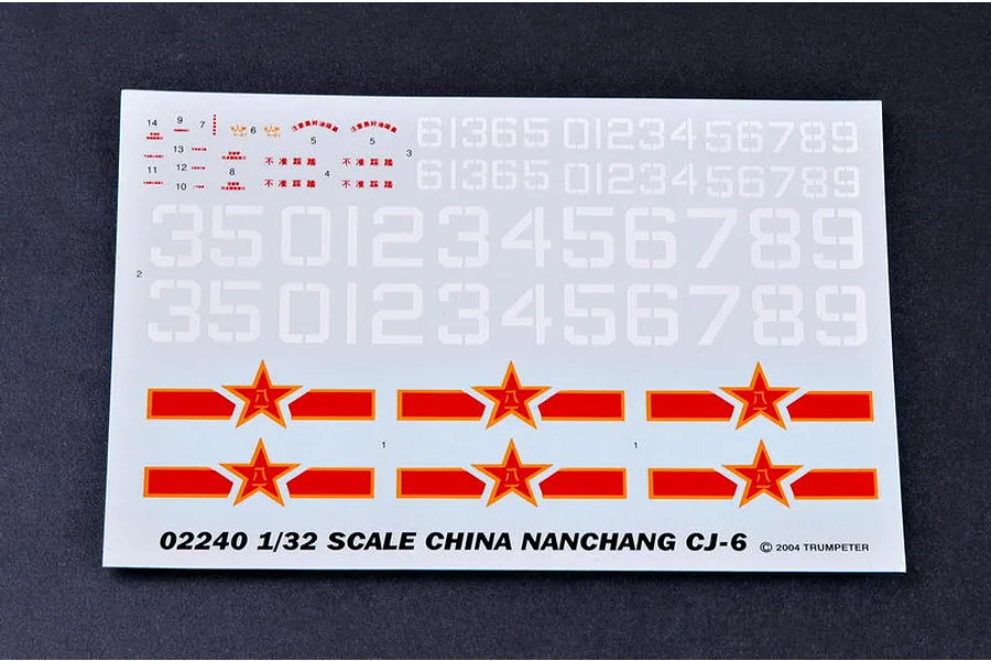 A decal sheet for a 1/32 scale Trumpeter Nanchang CJ-6 model kit, featuring various numbers, Chinese military insignias, and small warning labels.