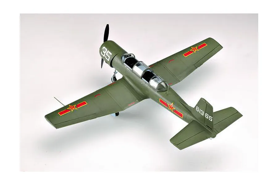 A high-angle studio shot of a completed 1/32 scale Nanchang CJ-6 trainer model aircraft painted in olive green with red star markings.