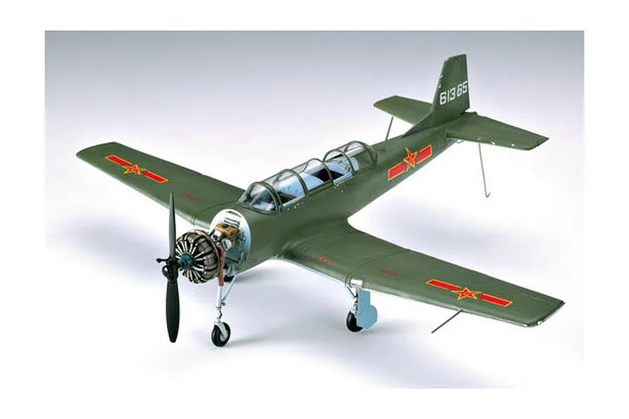 A 1/32 scale plastic model of a Nanchang CJ-6 trainer aircraft in olive green with red star markings, shown from a high-angle front view.