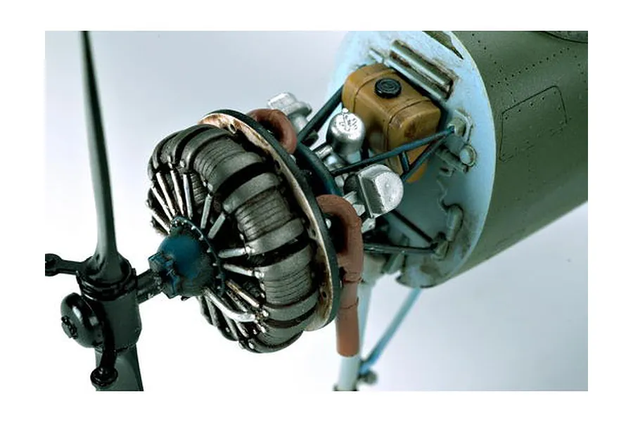 Close-up of a detailed scale model aircraft engine and propeller assembly, showing the radial engine cylinders, exhaust pipes, and fuselage section.