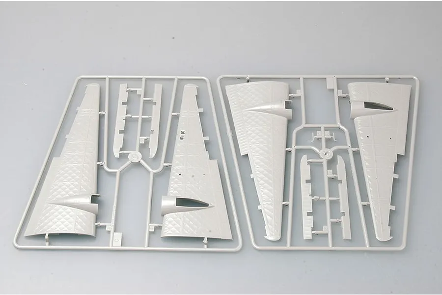 Two grey plastic model kit sprues containing aircraft wing sections and control surfaces on a plain light grey background.