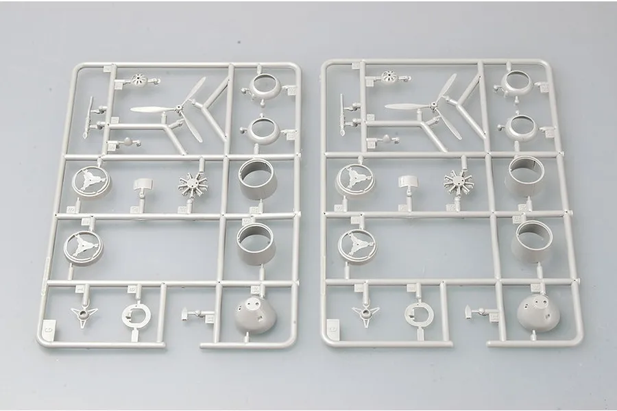 Two identical grey plastic model kit sprues containing aircraft engine parts, propellers, and cowlings on a light grey background.