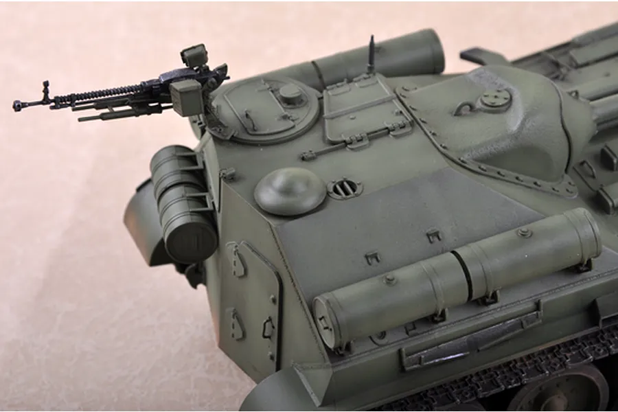 A close-up view of a 1/35 scale model Soviet SU-101 self-propelled gun, showing the olive green hull, machine gun, and external fuel tanks.