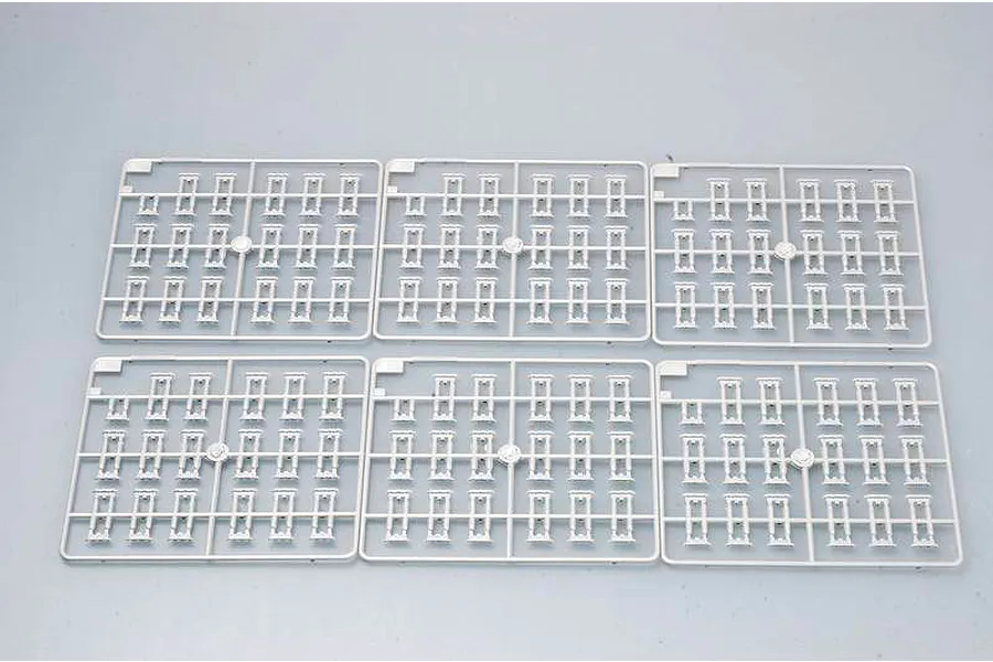 Six identical grey plastic model kit sprues containing individual tank track links, arranged in two rows of three on a light grey background.