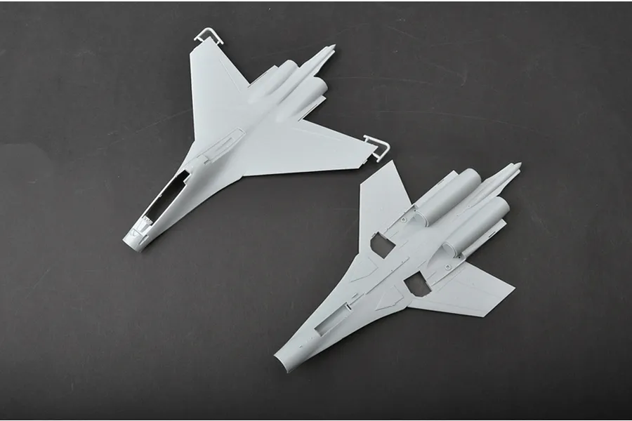Top and bottom views of unpainted grey plastic model aircraft fuselage parts for a Trumpeter Su-30MKK kit on a dark grey background.
