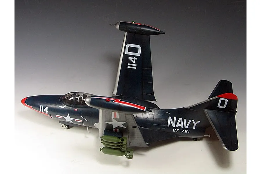 A completed 1/48 scale model of a US Navy F9F Panther jet with wings folded, painted in dark blue with red accents and military markings.