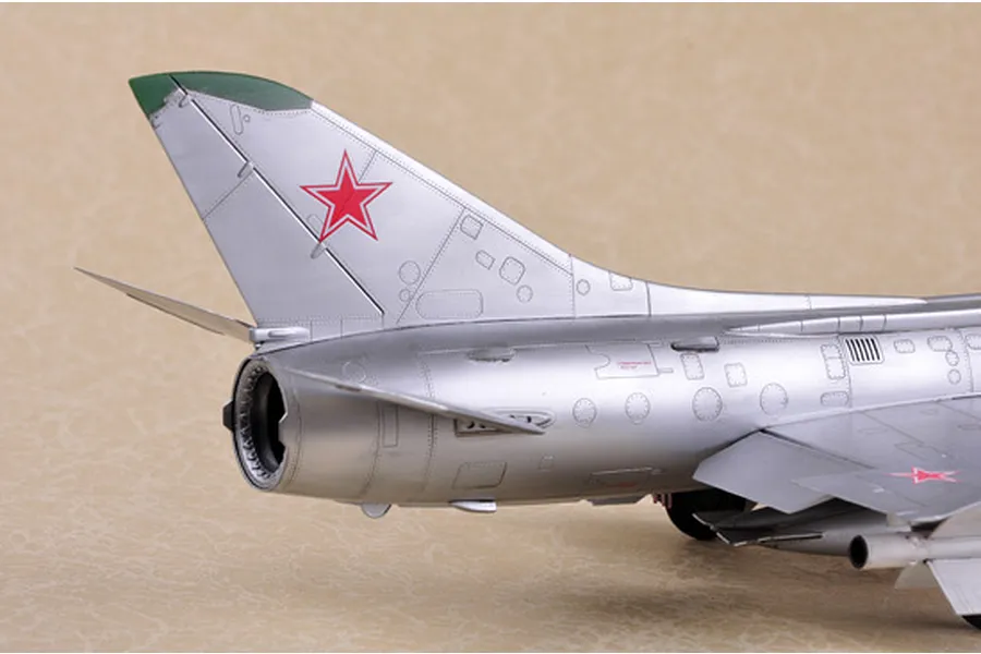 Close-up of the tail section of a silver scale model Su-11 Fishpot jet with a red star insignia on the vertical stabilizer.