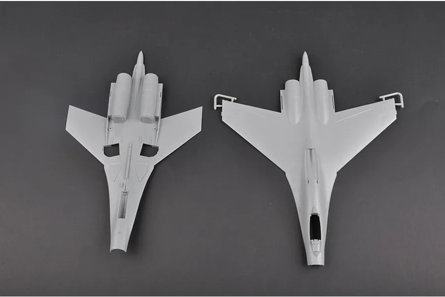 Top-down view of two unpainted grey plastic model aircraft fuselage and wing sections from a Trumpeter 1/72 Su-27 kit.