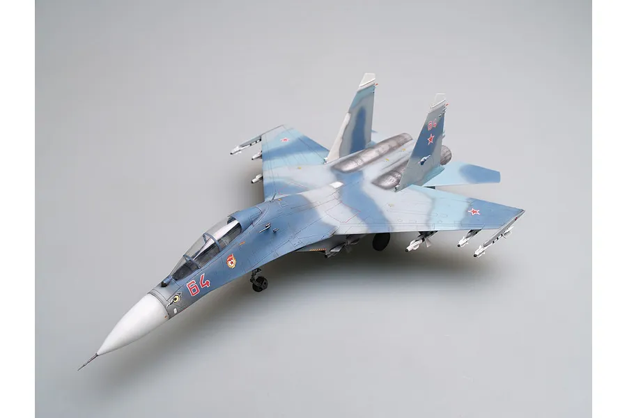 A completed 1/72 scale plastic model of a Russian Su-27UB fighter jet, painted in a blue and grey camouflage scheme with red number 64 on the nose.