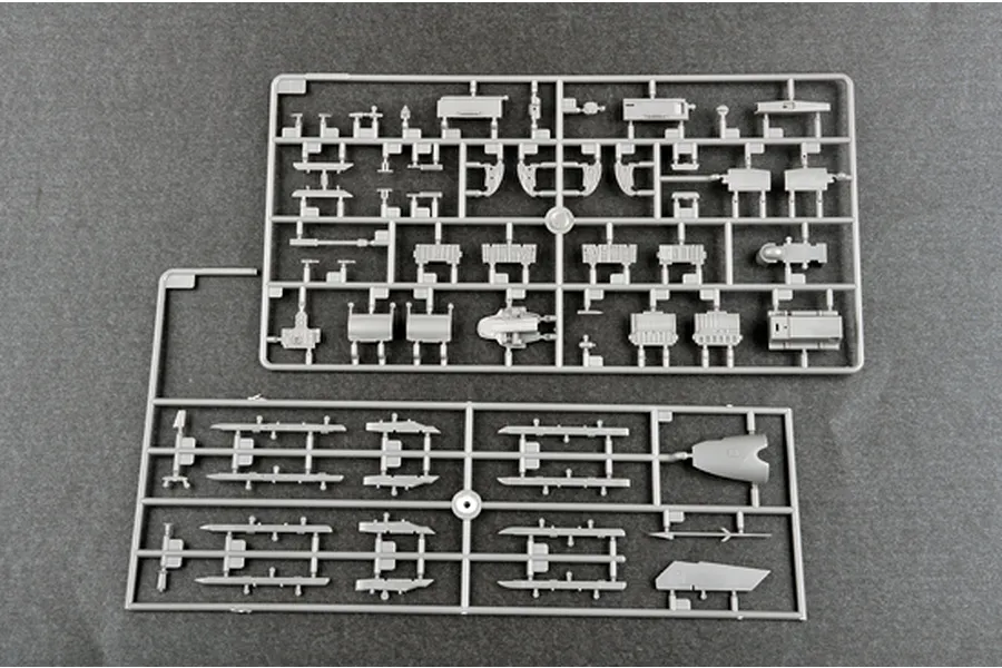 Two grey plastic model kit sprues containing various aircraft parts, including missile rails and structural components, on a dark grey background.