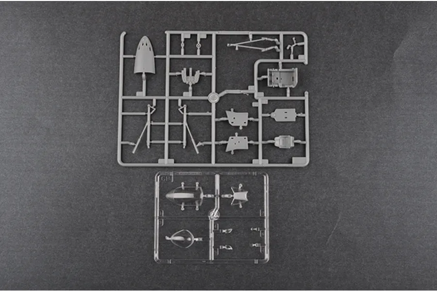 Two plastic model kit sprues for a 1/48 scale aircraft, one grey and one clear, laid out on a dark grey surface.