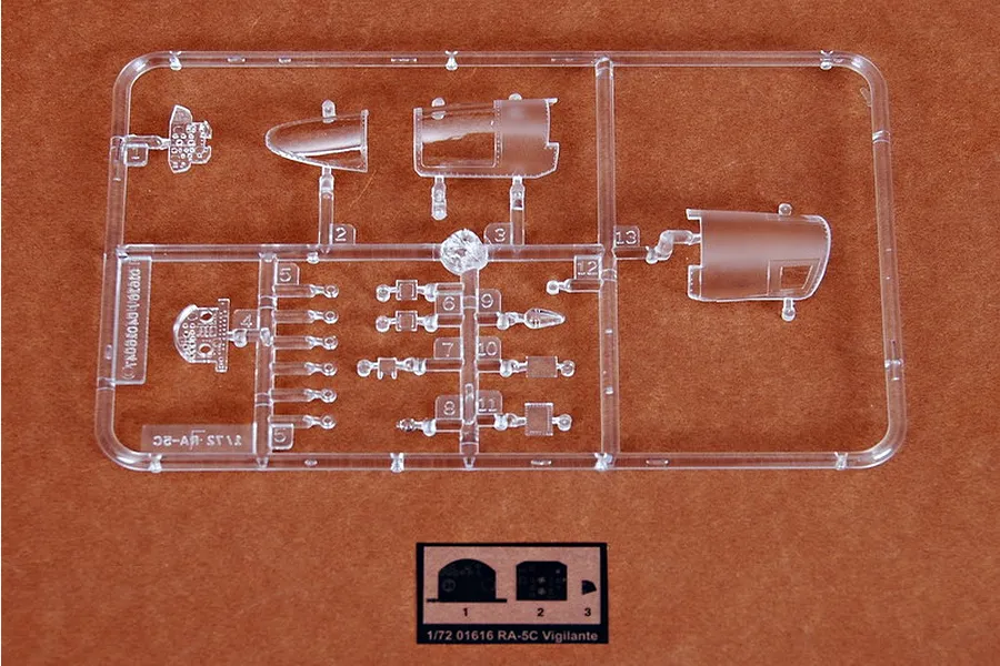 A clear plastic sprue containing canopy and cockpit parts for a 1/72 scale Trumpeter RA-5C Vigilante model kit, set against a brown background.