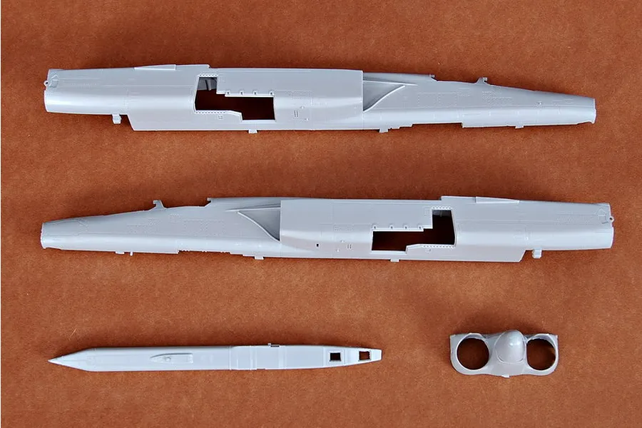 Plastic model kit parts for a Trumpeter 1/72 RA-5C Vigilante jet, showing two fuselage halves, a nose cone, and an intake section on a brown background.