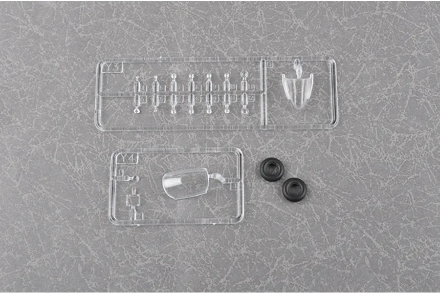 Clear plastic model kit sprues labeled Y3 and Y4, including a canopy part and two small black rubber tires on a grey textured background.