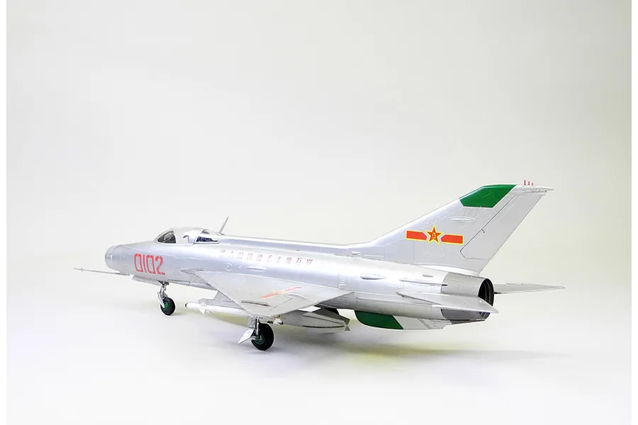 A side-profile view of a fully assembled and painted 1/48 scale MiG-21F-13 model aircraft in a silver finish with red and green markings.