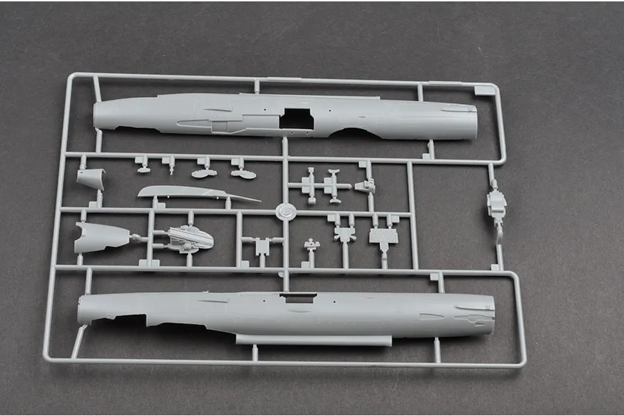 A grey plastic sprue containing fuselage halves and various small components for a 1/48 scale MiG-21F-13 model aircraft kit.