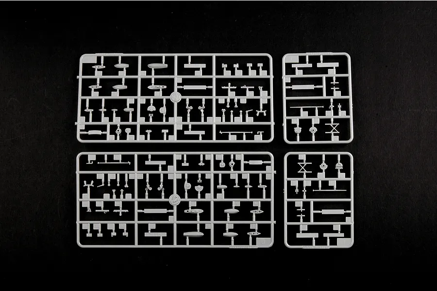 Four grey plastic model kit sprues containing various small ship parts, including lifeboats and masts, laid out on a black background.