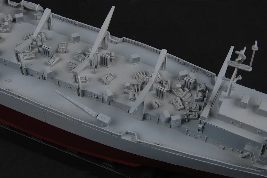 Close-up of the deck of a 1/700 scale plastic model battleship, showing grey molded details like cranes, anti-aircraft guns, and superstructure.