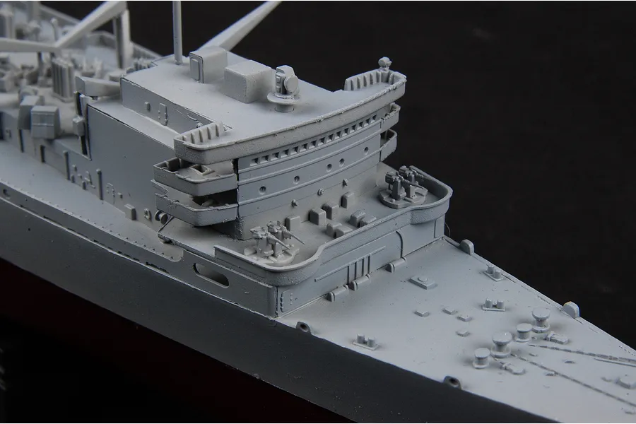 Close-up of the grey plastic superstructure of a 1/700 scale model battleship, showing deck details, anti-aircraft guns, and bridge structure.